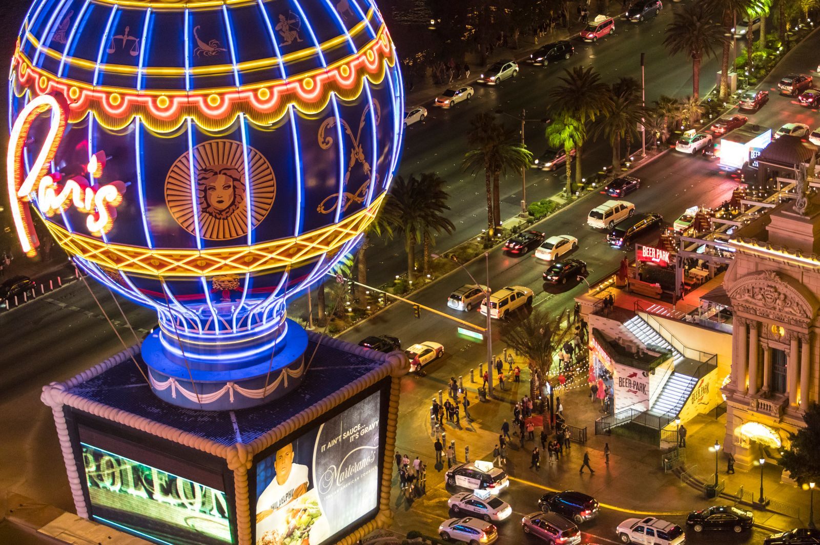 The neon hot-air balloon sign of Paris Las Vegas above crowds and traffic on the Strip at night