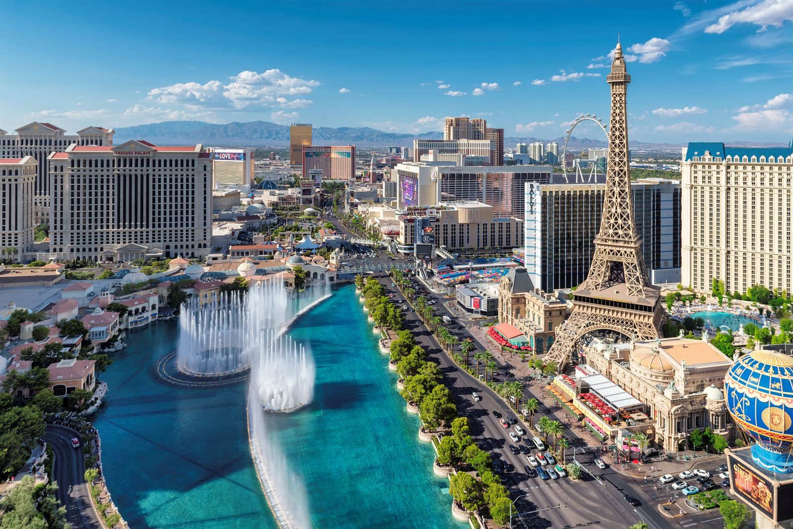 The Bellagio fountains, one of the free things to do in Las Vegas, spraying in the lake below the Paris Eiffel Tower replica on a sunny day